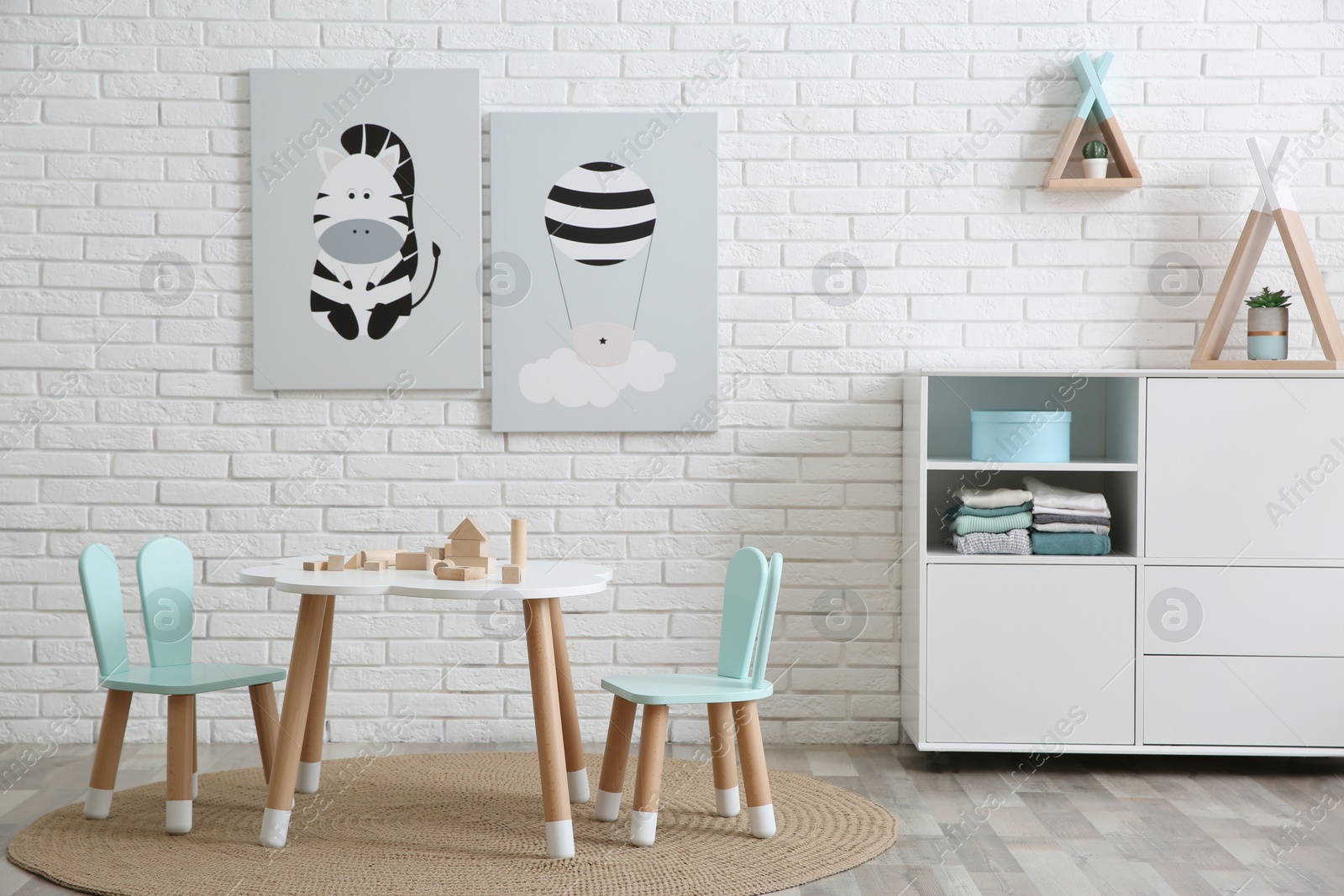 Photo of Cute children's room interior with little table near white brick wall