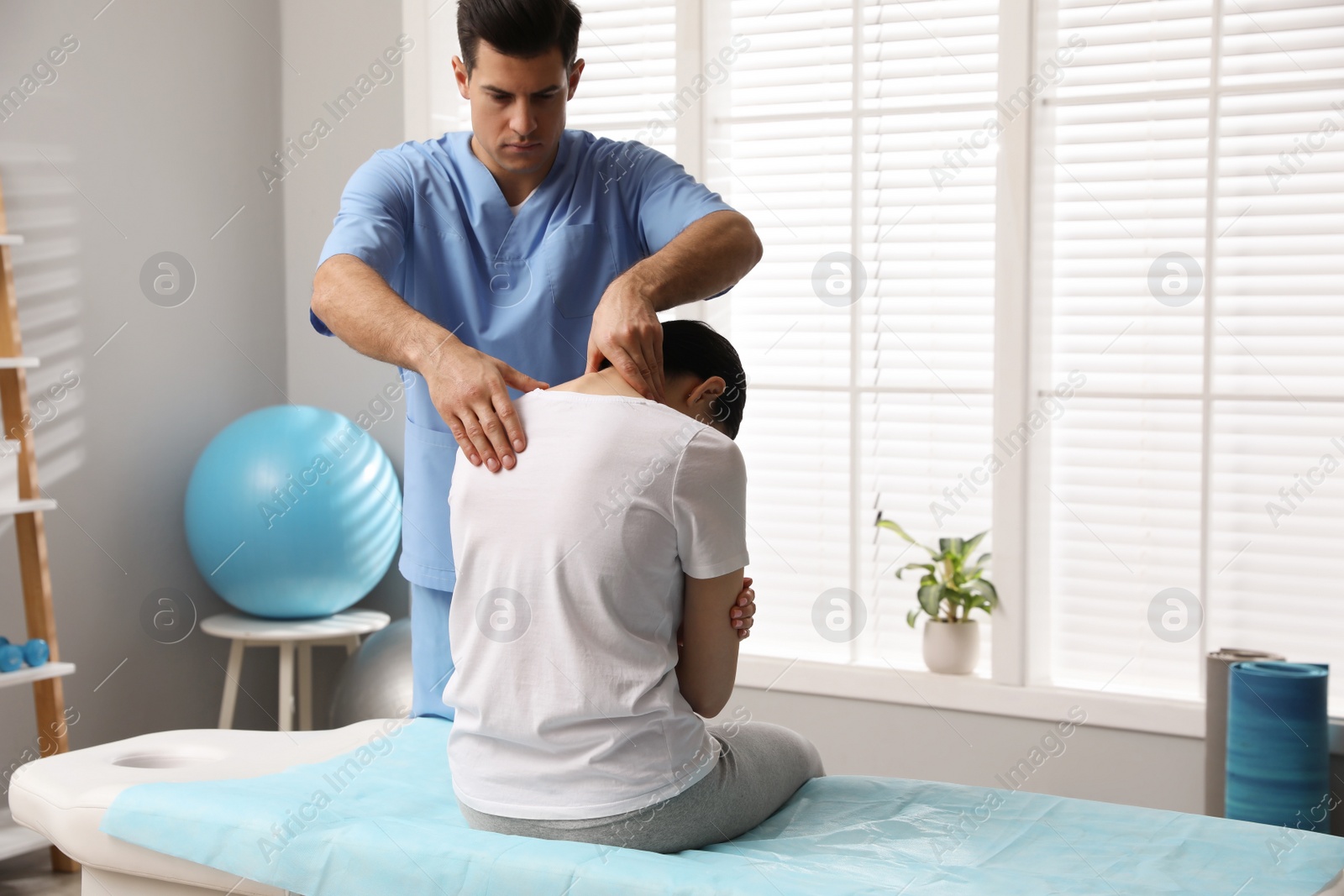 Photo of Orthopedist examining woman's neck in clinic, space for text. Scoliosis treatment