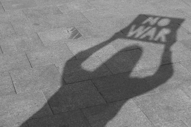 Photo of Shadow of woman holding poster with words No War outdoors