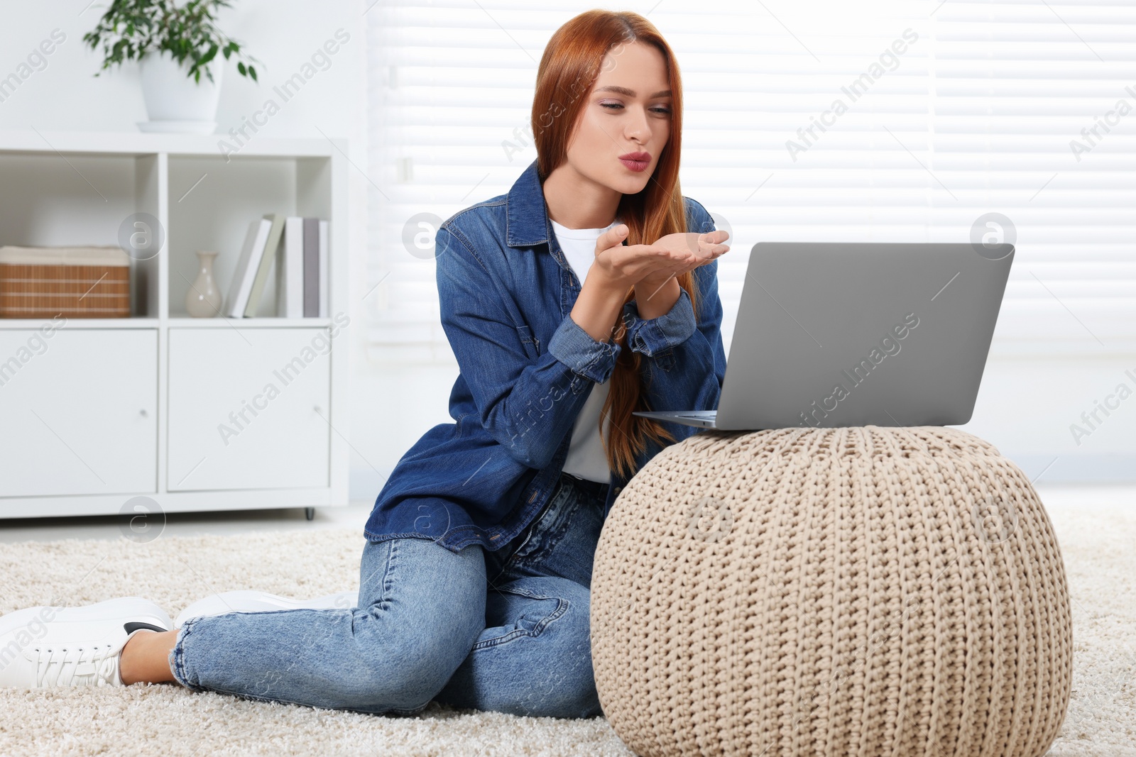 Photo of Woman blowing kiss during video chat via laptop at home. Long-distance relationship