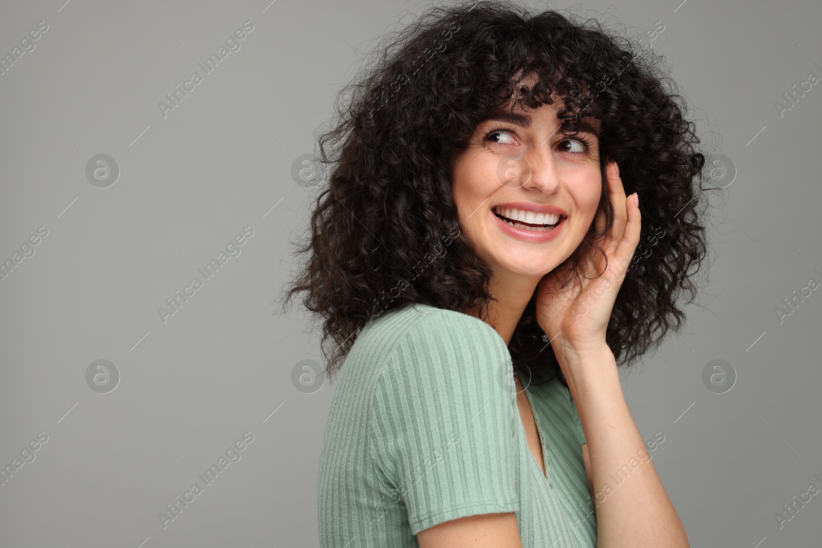 Photo of Young woman using teeth whitening strip on grey background, space for text