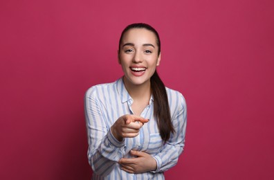 Beautiful young woman laughing on maroon background. Funny joke