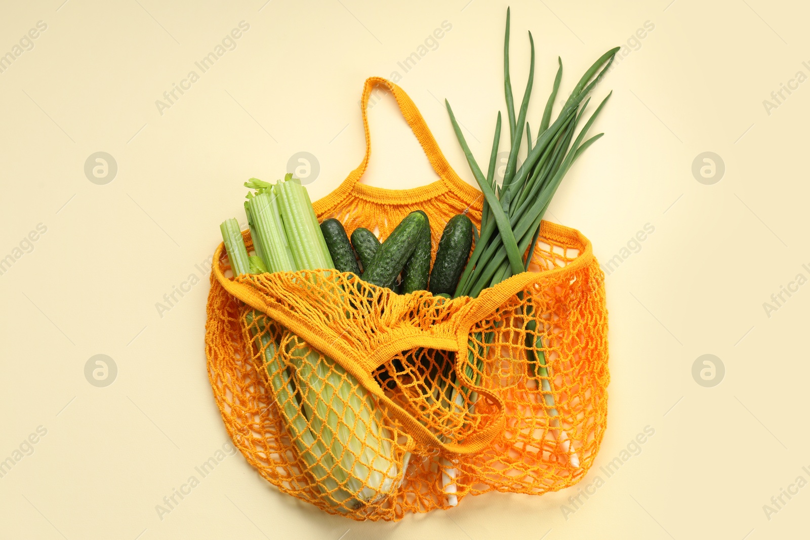 Photo of String bag with different vegetables on beige background, top view