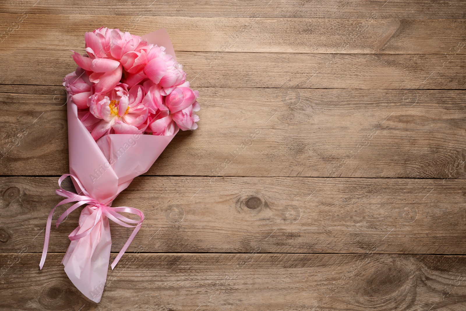 Photo of Beautiful bouquet of pink peonies on wooden table, top view. Space for text