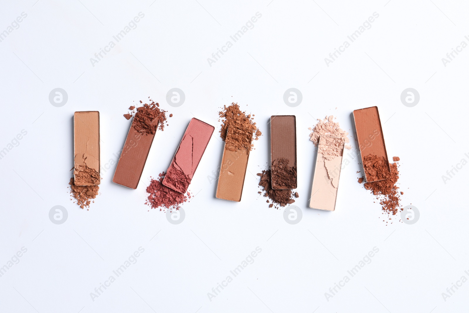 Photo of Different crushed eye shadows on white background, flat lay. Professional makeup product