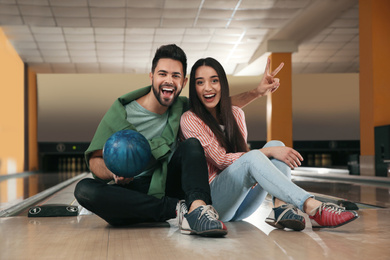 Happy young couple with ball in bowling club