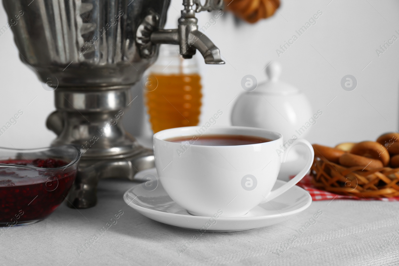 Photo of Delicious ring shaped Sushki (dry bagels), focus on cup of tea and samovar. Space for text copy