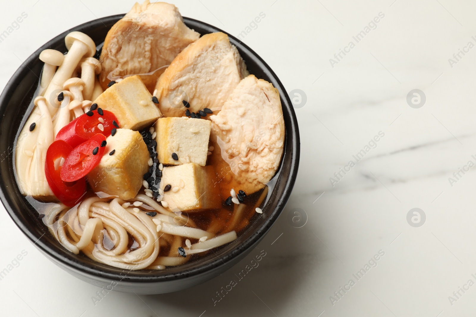 Photo of Bowl of delicious ramen on white table, space for text. Noodle soup