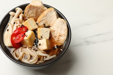 Bowl of delicious ramen on white table, space for text. Noodle soup