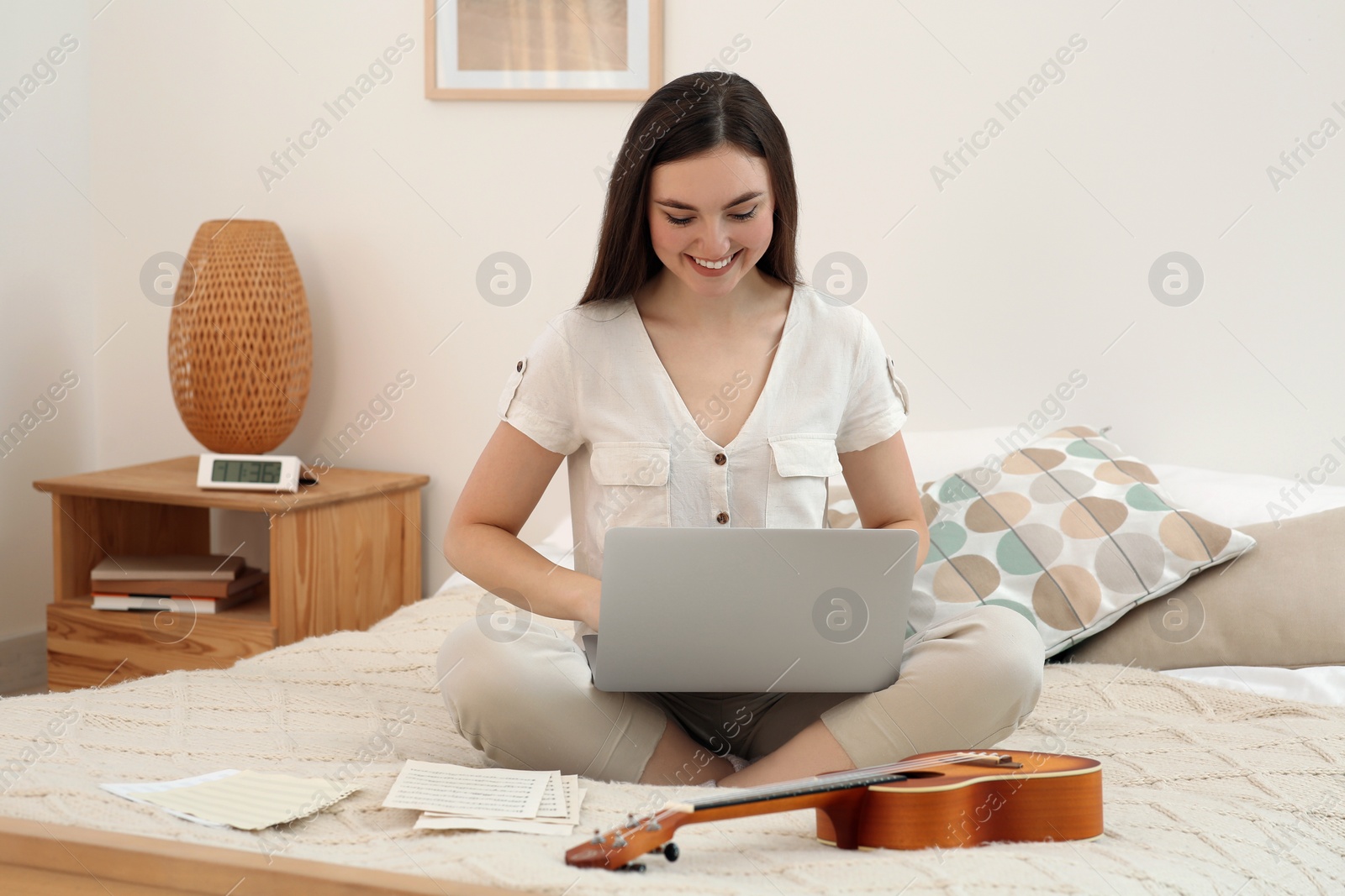 Photo of Woman learning to play ukulele with online music course at home. Time for hobby