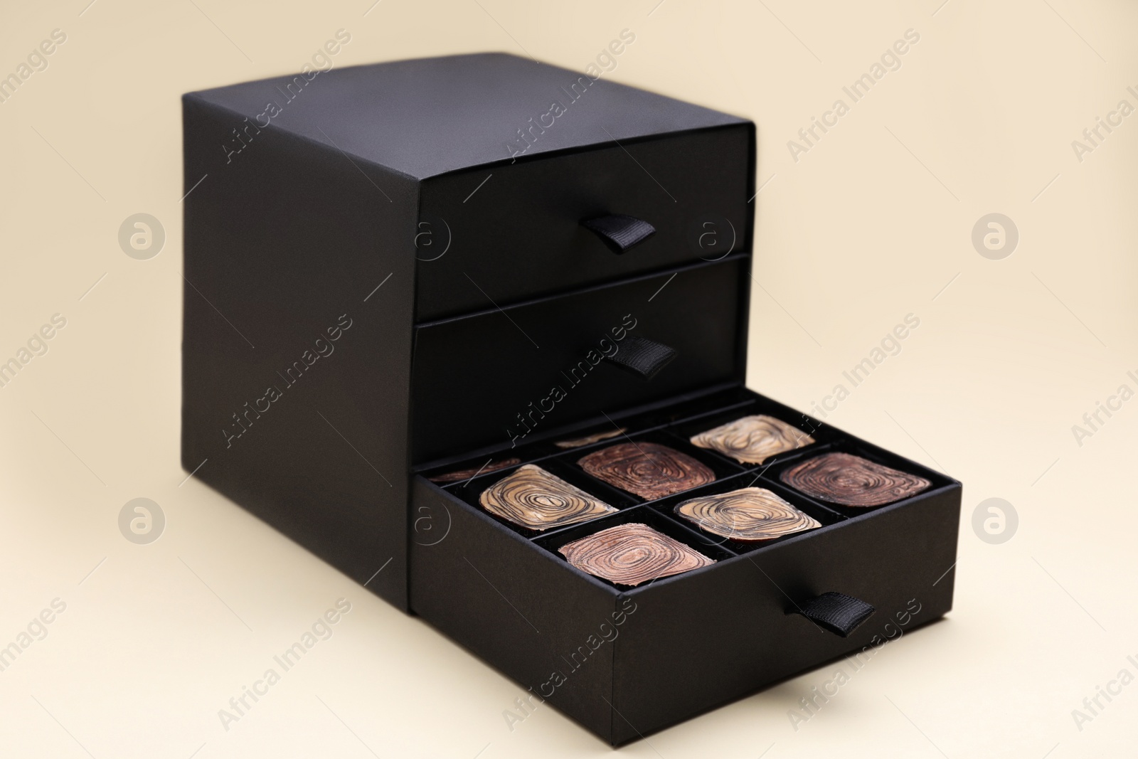 Photo of Box of tasty chocolate candies on beige background