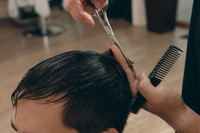 Professional hairdresser working with client in barbershop, closeup