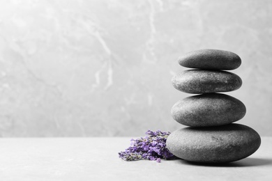 Photo of Spa stones and lavender flowers on grey table, space for text