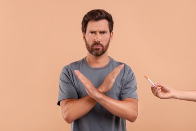 Photo of Stop smoking concept. Man refusing cigarette on light brown background