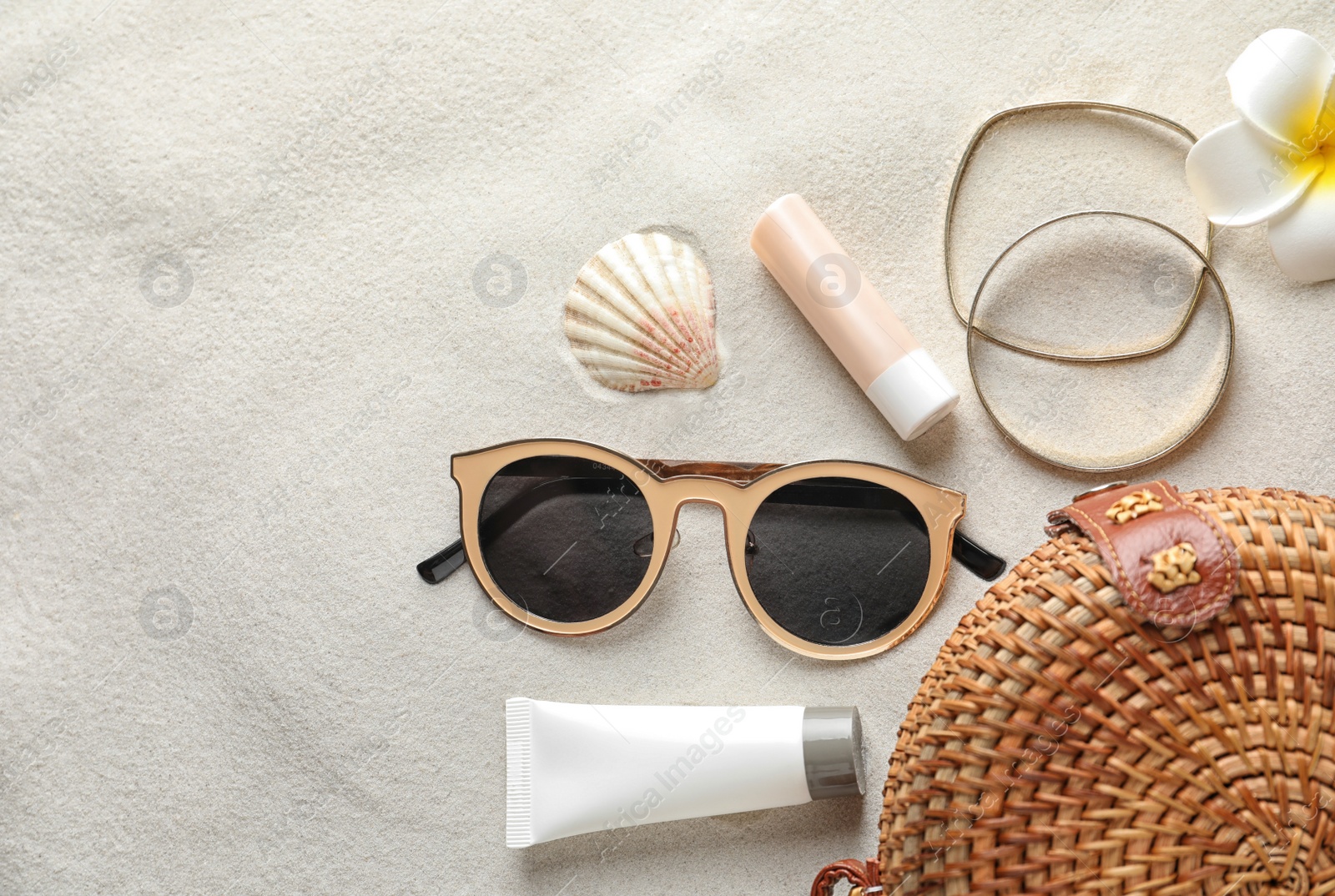 Photo of Flat lay composition with sun protection cosmetic products on sand, space for text