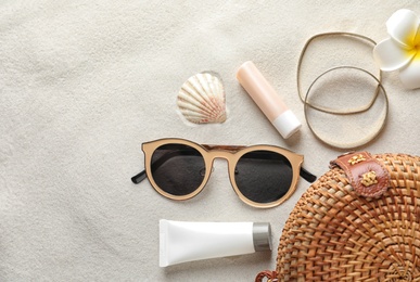 Photo of Flat lay composition with sun protection cosmetic products on sand, space for text