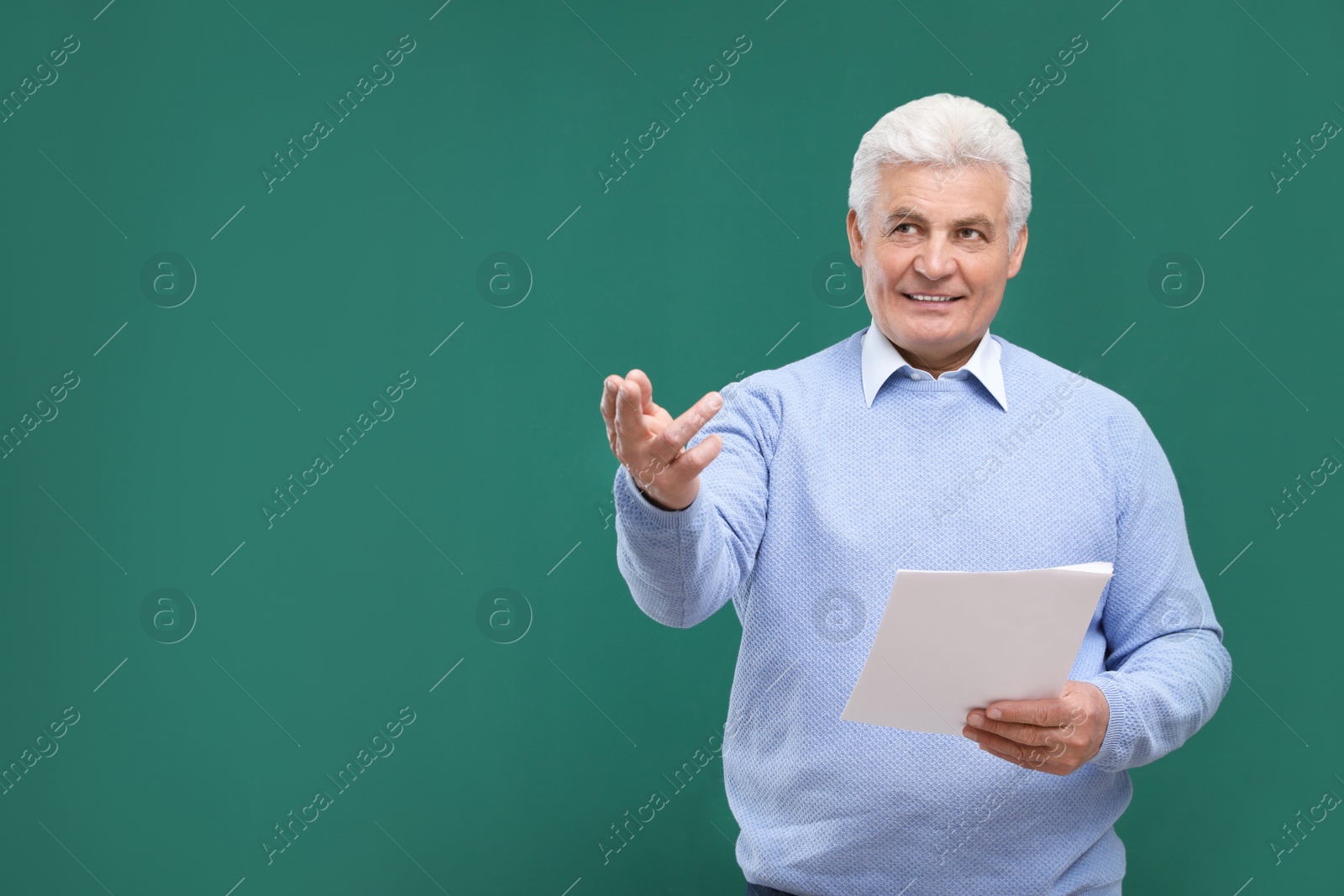 Photo of Portrait of senior teacher with paper at green chalkboard, space for text