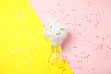 Glass with cotton candy on color background, top view