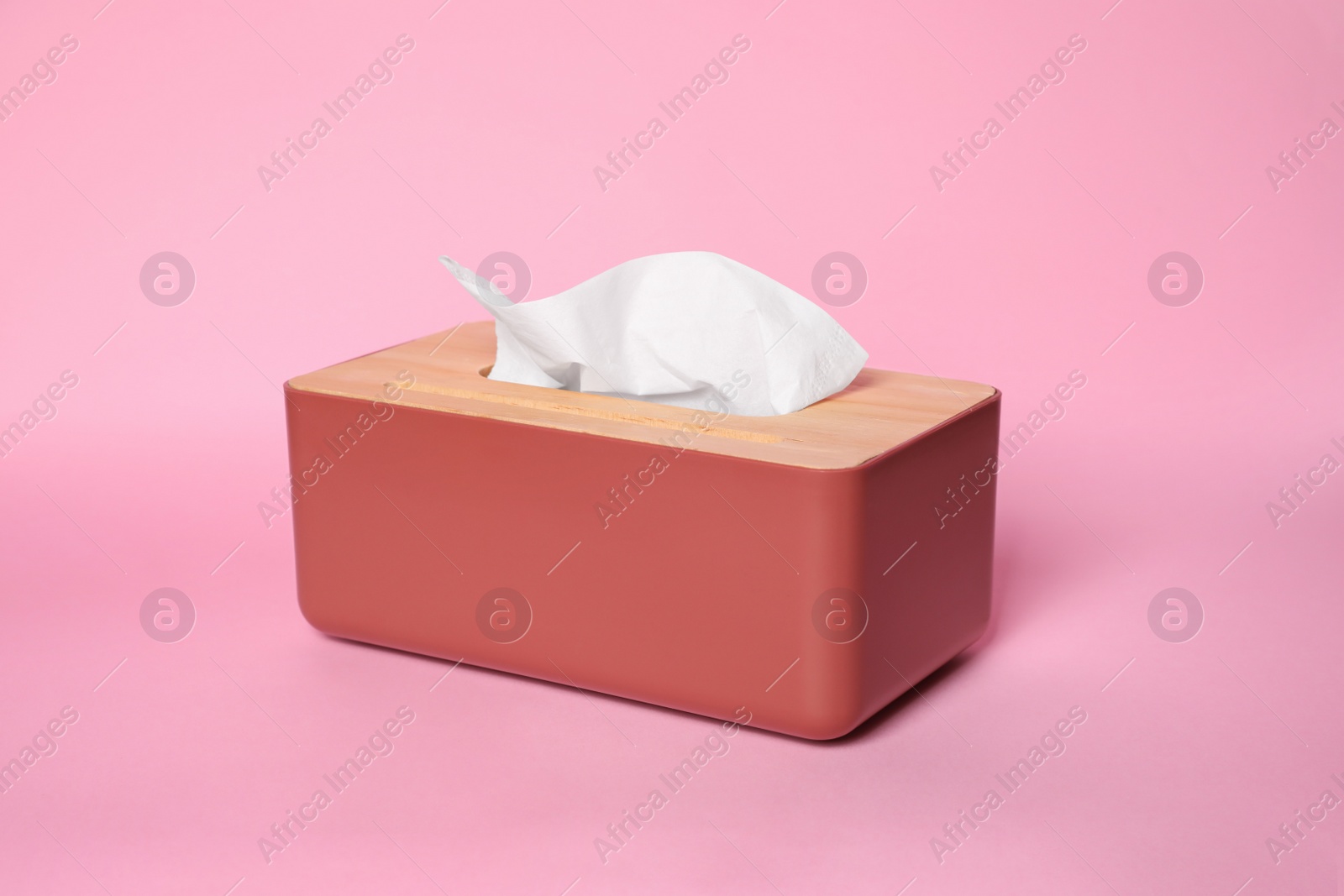 Photo of Holder with paper tissues on pink background