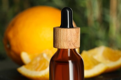 Photo of Bottle of citrus essential oil on blurred background, closeup