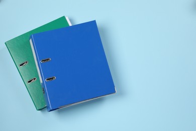 Office folders on light blue background, flat lay. Space for text