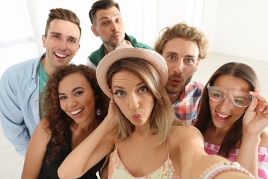 Group of happy young people taking selfie indoors