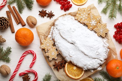 Photo of Traditional Christmas Stollen with icing sugar on white wooden table, flat lay