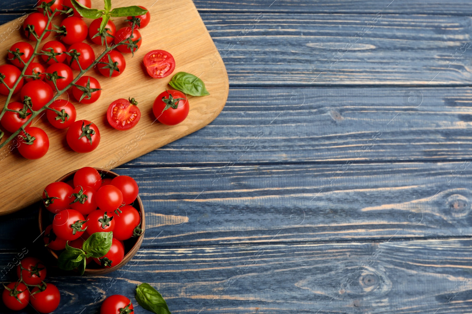 Photo of Fresh ripe cherry tomatoes and basil on blue wooden table, flat lay. Space for text