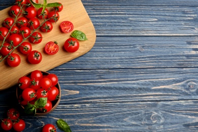 Photo of Fresh ripe cherry tomatoes and basil on blue wooden table, flat lay. Space for text