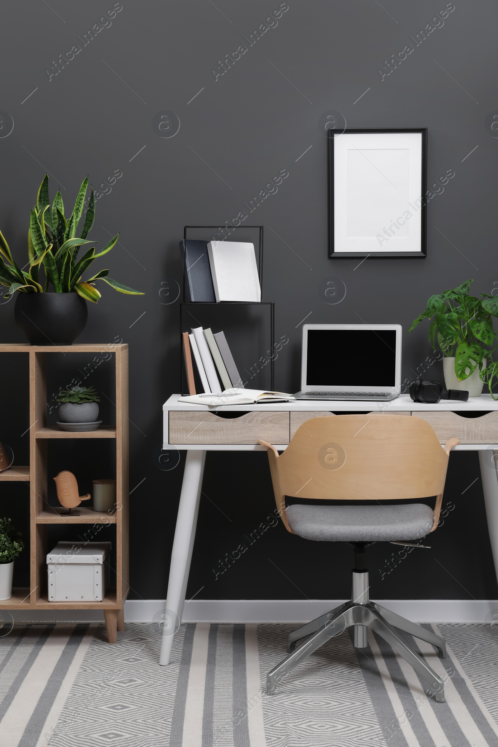 Photo of Workplace with laptop, stationery on desk and chair in home office