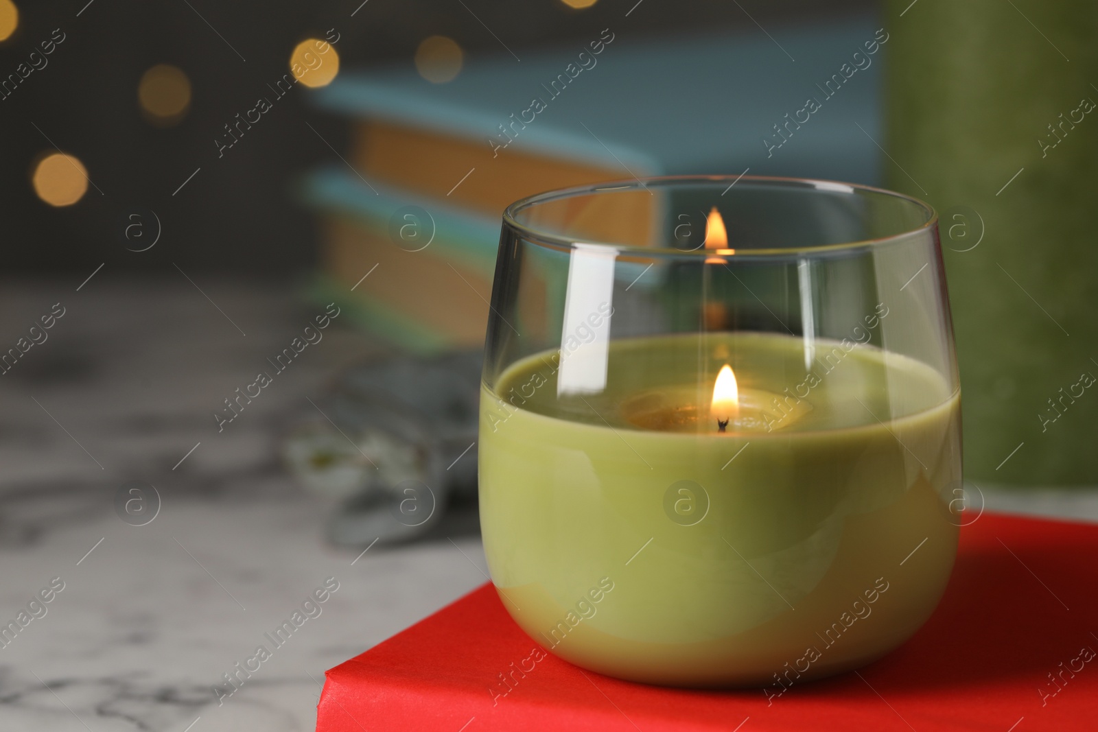 Photo of Burning candle and book on white marble table, space for text