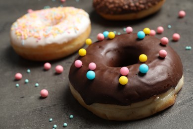 Yummy donut with colorful sprinkles on dark table, closeup
