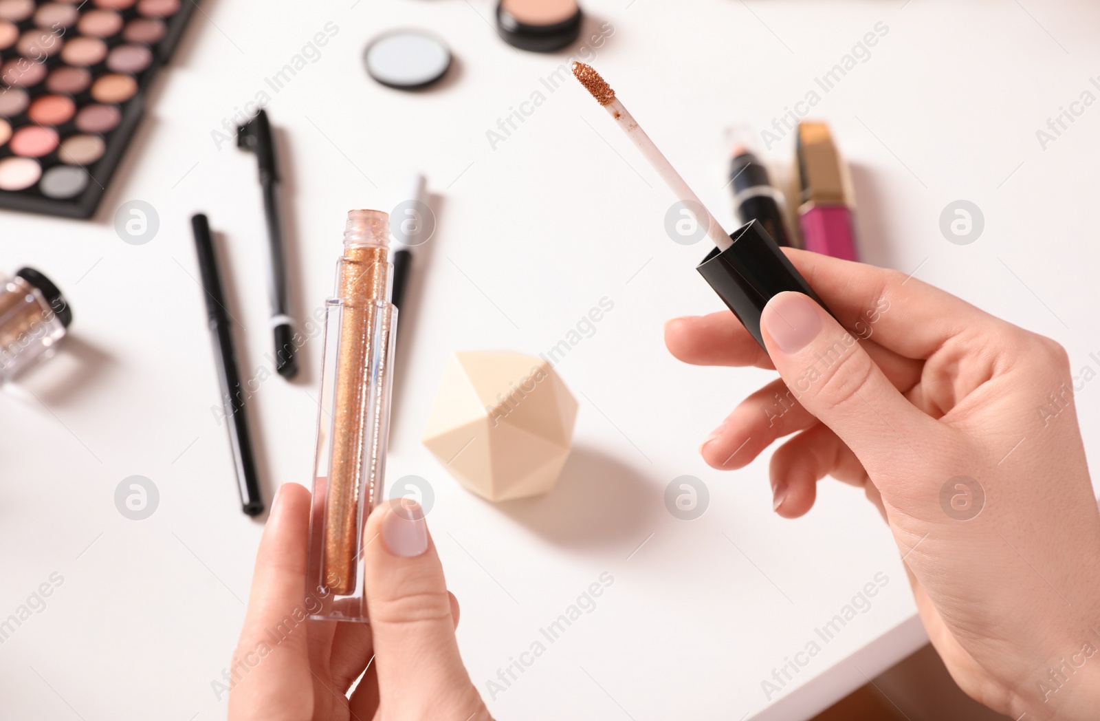 Photo of Beauty blogger with liquid eyeshadow at table, closeup