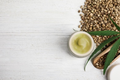 Photo of Jar of hemp cream and seeds on white wooden table, flat lay with space for text. Organic cosmetics