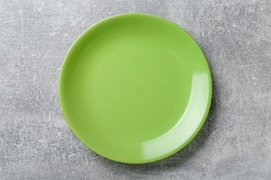 Photo of Empty green ceramic plate on light grey table, top view