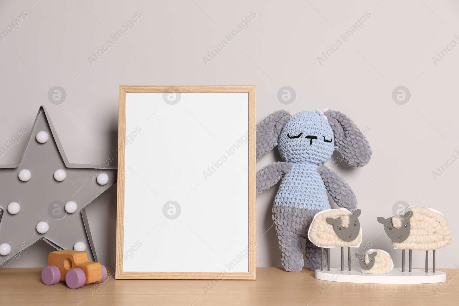 Photo of Empty square frame and different toys on wooden table