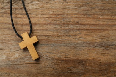 Christian cross on wooden table, top view. Space for text
