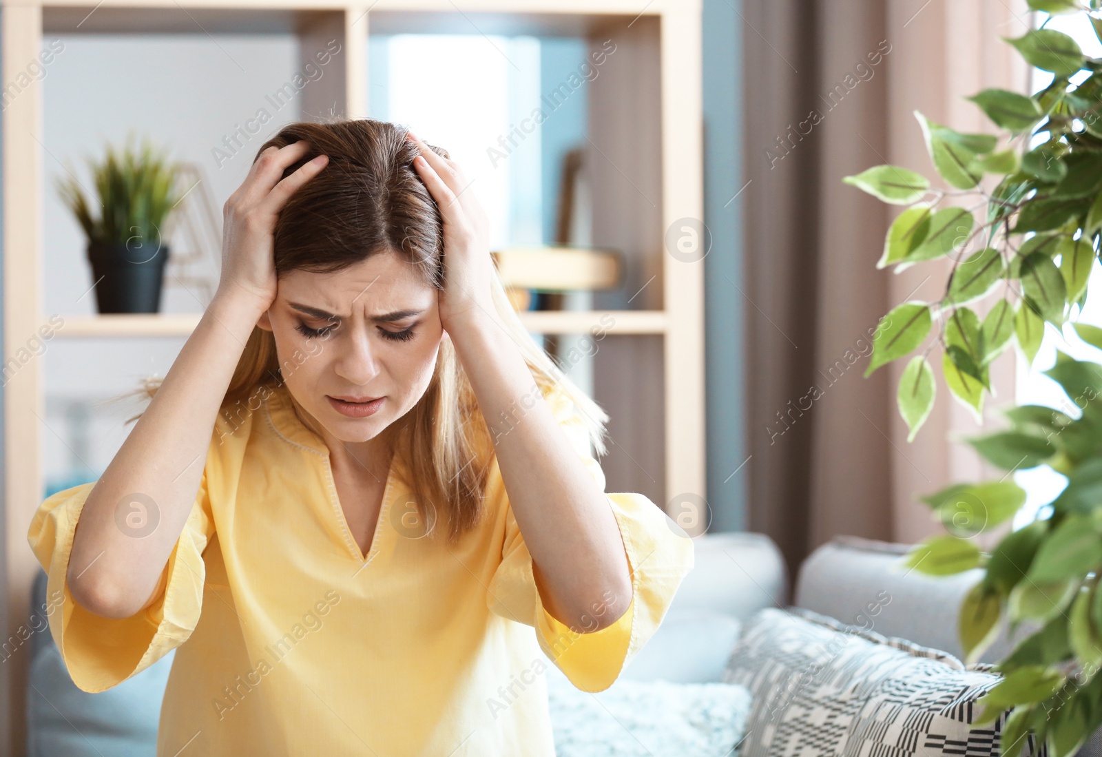 Photo of Young woman suffering from headache at home