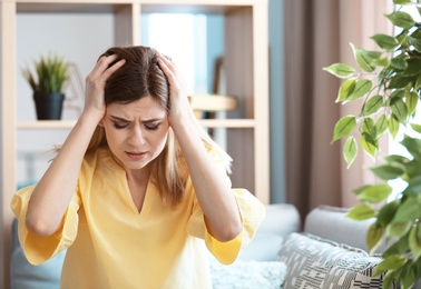 Photo of Young woman suffering from headache at home