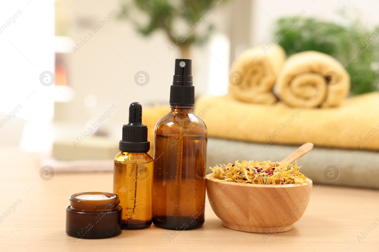 Photo of Bottles of essential oils, dry flowers and jar with cream on light wooden table. Spa therapy