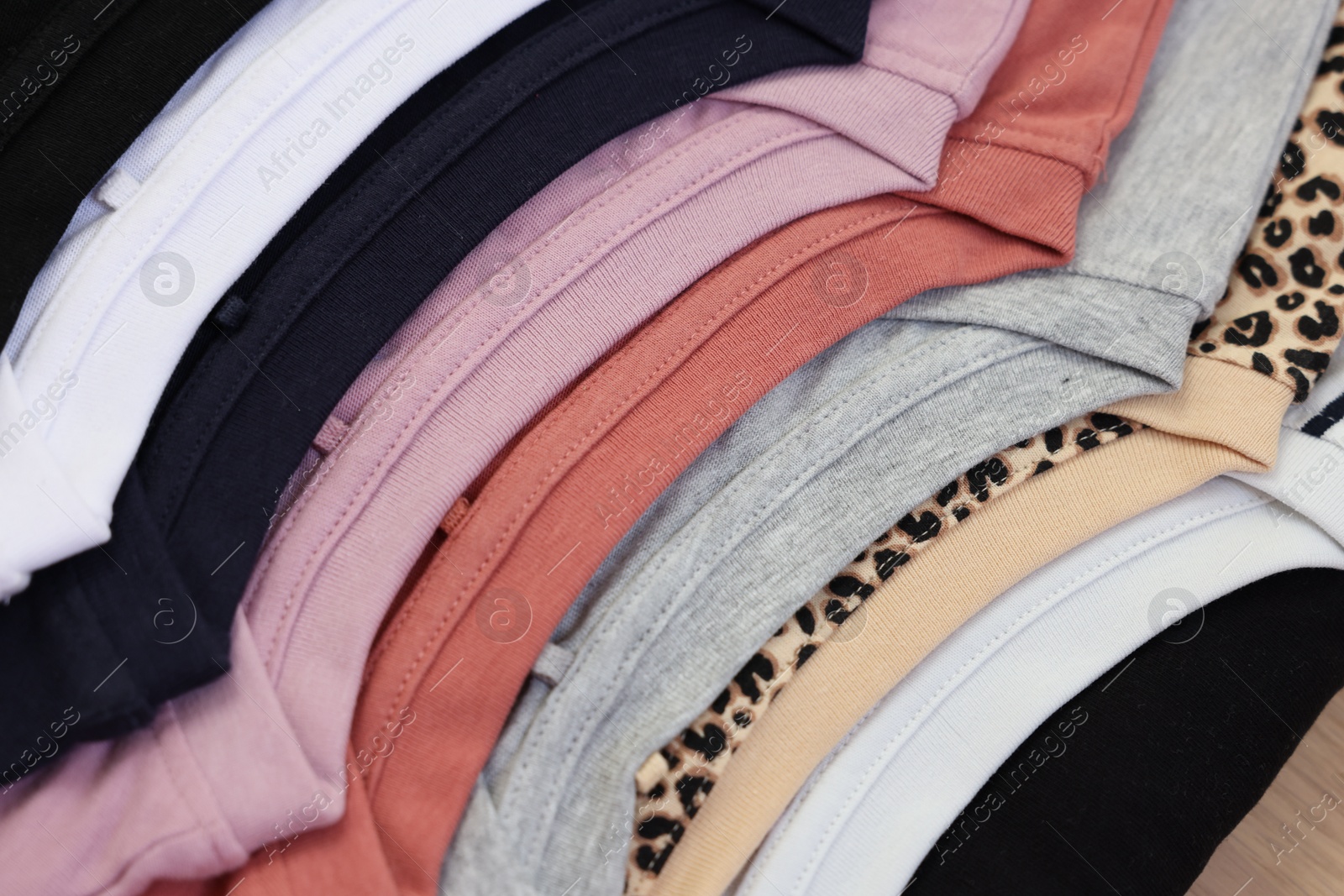 Photo of Many stacked clothes on wooden table, top view