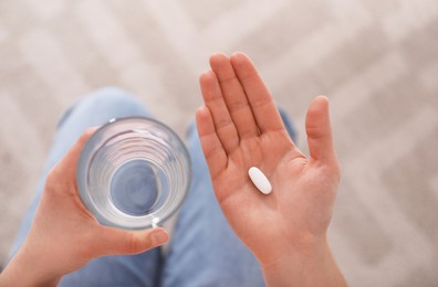 Photo of Young woman with abortion pill and glass of water, top view