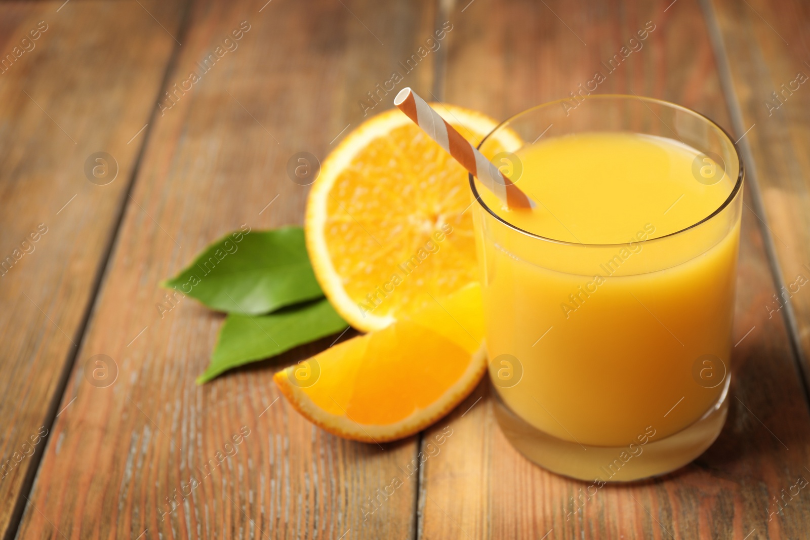 Photo of Glass of orange juice and fresh fruits on wooden table. Space for text