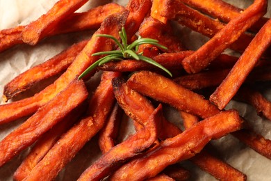 Photo of Delicious sweet potato fries and sauce on parchment paper, closeup