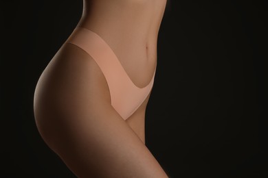 Photo of Closeup view of slim woman in underwear on black background, space for text. Cellulite problem concept