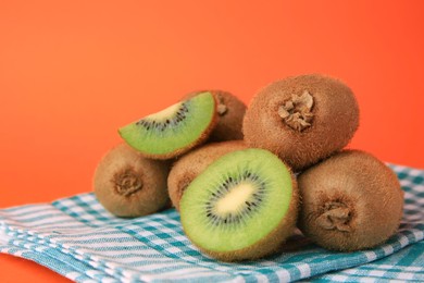 Heap of whole and cut fresh kiwis on orange background