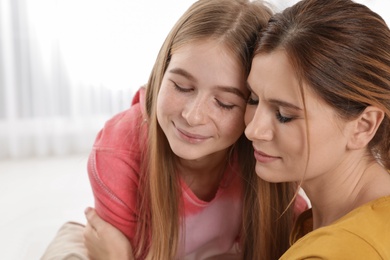 Happy mother hugging her teenager daughter at home