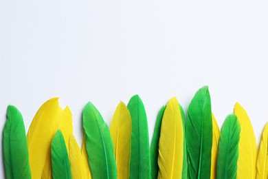 Photo of Bright feathers on white background, flat lay. Space for text