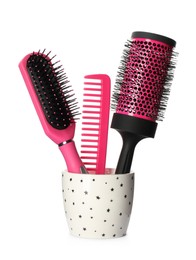 Photo of Hairbrushes and comb in holder on white background