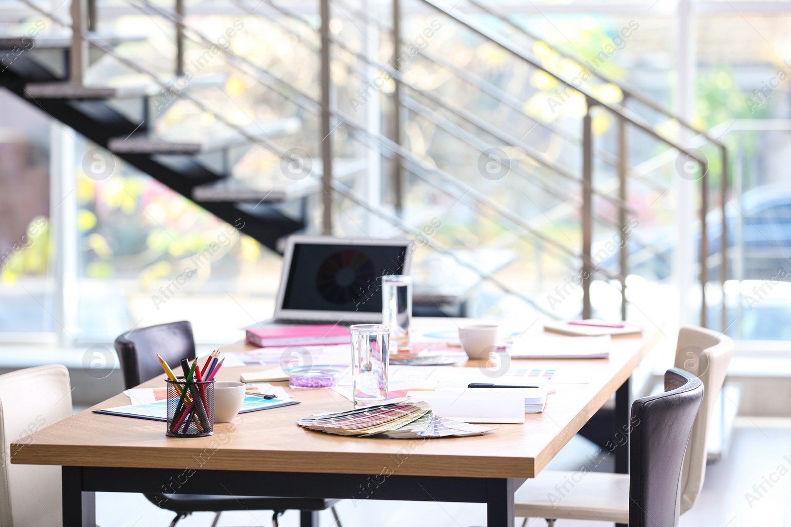 Photo of Meeting table with laptop and color palettes in interior designer's office